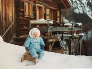 Priska sitzt auf einem Holzschlitten im Schnee.