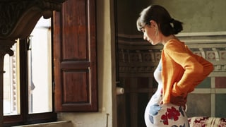 Schwangere Frau steht vor Fenster