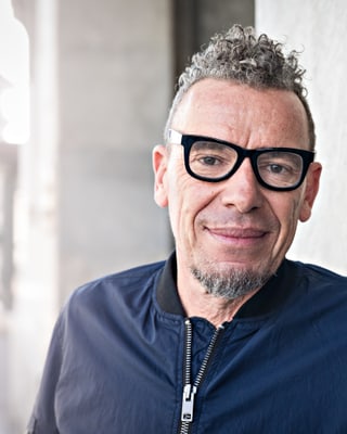 Autor Tom Kummer mit schwarz umrandeter Brille und dunkler Bomberjacke. Autor Tom Kummer mit schwarz umrandeter Brille und dunkler Bomberjacke.