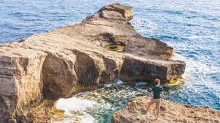 Ein Mann auf einem Felsen am Meer. 