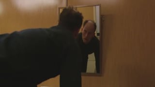 Ein Mann schaut sich im Spiegel an.
