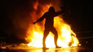 Ein Mann steht vor einem Feuer Ein Mann steht vor einem Feuer