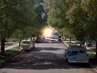 Ein Auto schwebt eine Strasse hinunter begleitet von einem Lichtblitz.