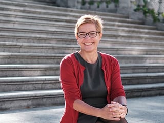 Frau sitzt draussen auf einer Treppe.