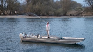 Mann in Boot stehend spuckt Wasser im hohen Bogen Mann in Boot stehend spuckt Wasser im hohen Bogen