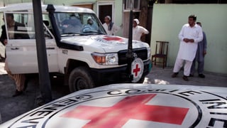 Ein weisser Jeep mit dem roten IKRK-Logo steht vor einem Haus in Afghanistan.