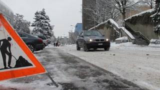 Eine Strasse mit Schnee, darauf ein Auto.
