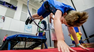 Junge springt von Trampolin durch einen Ring