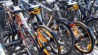 öffentlicher Veloständer mit zwei orangen O-Bikes zwischen anderen Fahrrädern
