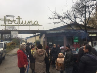 Am Fabrikeingang steht eine Gruppe von Protestierenden.