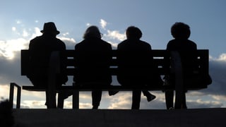 Vier Rentner sitzen auf einer Bank.