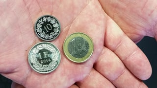 Hand hält Geldstücke: 1 Euro, 1 Franken und ein 10-Räppler. 