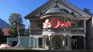 Das Haus für Kunst in Uri mit rosafarbenen Satellitenschüsseln auf dem Balkon.