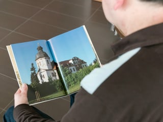 Ein Mann betrachtet ein Buch mit Bildern aus Thüringen.