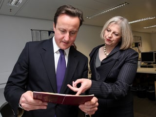 Theresa May zeigt David Cameron echte und gefälschte Pässe. 