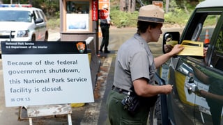 Eine Nationalpark-Angestellte überprüft einen Autofahrer.