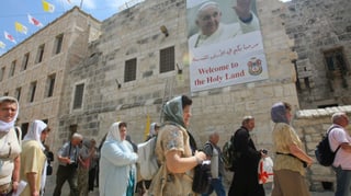 Touristen vor der Geburtskirche in Bethlehem, an der ein Poster mit dem Papst hängt