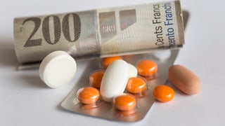 Ein Geldschein von 200 Franken und mehrere Pillen zeigen, wie teuer Medikamente sind.
