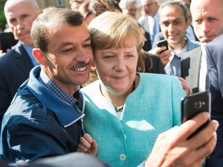 Bundeskanzlerin Angela Merkel macht ein Selfie mit einem Flüchtling.