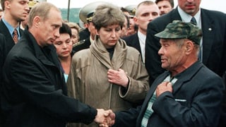 Putin schüttelt Mann die Hand.