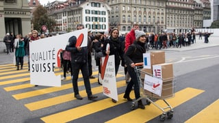 Unterstützer der Konzernverantwortungsinitiative gehen mit Einkaufswagen über einen Zebrastreifen.