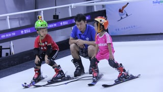 Zwei chinesische Kinder lernen Skifahren