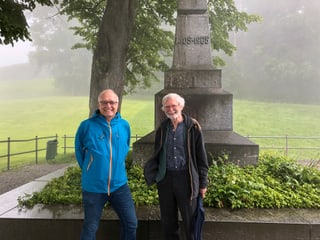 Zwei Männer vor einem Steindenkmal.