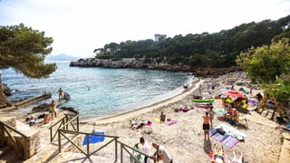 Kleine Sandstrandbucht mit Touristen und Meer Kleine Sandstrandbucht mit Touristen und Meer