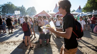 Viele Leute stehen auf Brettern, ein Mann trägt sein Essen vorbei.
