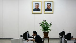 Ein Nordkoreaner sitzt an einem Computer, über ihm an die Wand gehängt ein Portrait von Kim Il-sun und Kim Jong-il. Ein Nordkoreaner sitzt an einem Computer, über ihm an die Wand gehängt ein Portrait von Kim Il-sun und Kim Jong-il.