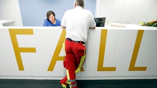 Ein Sanitäter steht an einer Empfangstheke mit der Aufschrift Notfall.