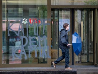 Ein Mann geht an einer UBS-Filiare vorbei. An der Fassade wurde «Kampf dem Kapital» gesprüht.