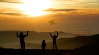 Familie lässt im Sonnenuntergang Drachen steigen