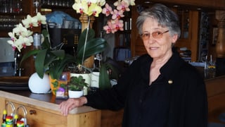 Frau an Bartresen neben Orchideen