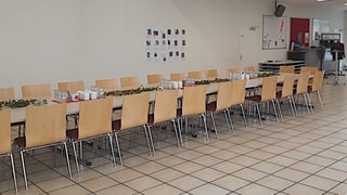 Ein grosser Tisch mit vielen Stühlen und Kaffeetassen darauf Ein grosser Tisch mit vielen Stühlen und Kaffeetassen darauf