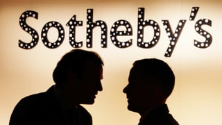 Im Hintergrund steht Sotheby's. Vorne diskutieren zwei Männer. Man sieht nur ihre Schatten.