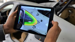 Ein Tablet scant die Oberfläche eines Autos und färbt Bereiche grün ein. Ein Tablet scant die Oberfläche eines Autos und färbt Bereiche grün ein.