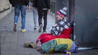 Bettler sitzt auf Trottoir, Leute gehen an ihm vorbei Bettler sitzt auf Trottoir, Leute gehen an ihm vorbei