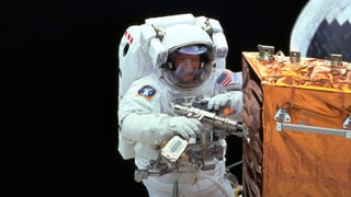 Mann in Astronautenanzug reapariert ein Weltraum Teleskop im Weltall.