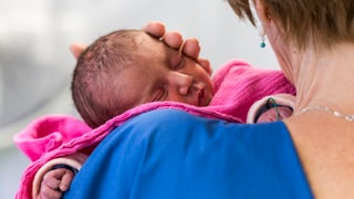 Krankenschwester mit Neugeborenem auf dem Arm