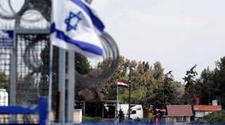 Israelisch Flagge und Grenzbefestigung, im Hintergrund syrische Flagge und Grenzposten.