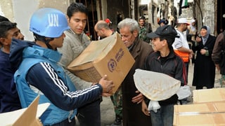 UNO-Soldaten verteilen Hilfsgüter in einem Flüchtlingslager in Damaskus.