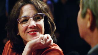 Bild aus dem Film: Dunkelhaarige Frau mit Brille im Gespräch mit einem Mann.
