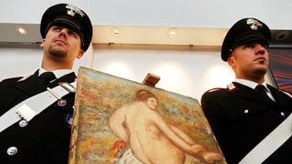 Zwei Polizisten stehen neben einem Gemälde.