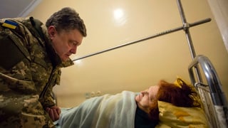 Ein Mann in Militärkleidung beugt sich über eine Frau auf einem Krankenbett. Ein Mann in Militärkleidung beugt sich über eine Frau auf einem Krankenbett.