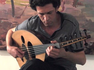 Der syrische Musiker Daisam Jalo spielt auf seinem Saiteninstrument.
