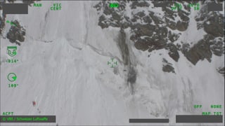 Luftaufnahme vom Absturzort zeigt Felsen und Schnee in steielem Gelände sowie ein rotes Wrackteil
