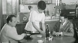 Schwarzweiss-Aufnahme: Eine Kellnerin bedient zwei Herren am Stammtisch.