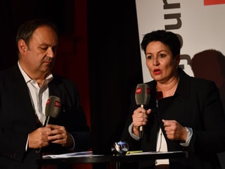 Zwei Personen mit Mikrophonen in der Hand. 