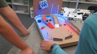 Kinderarme die einem leuchtenden Flipperkasten bauen. Kinderarme die einem leuchtenden Flipperkasten bauen.